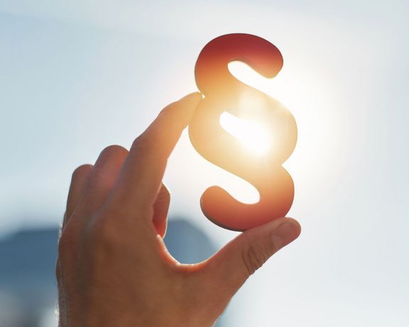 Datenschutz Eine Hand hält ein Paragraphenzeichen in die Sonne