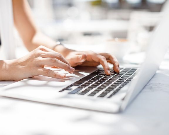 Frauenhände, die auf einer Laptop-Tastatur einen Text tippen